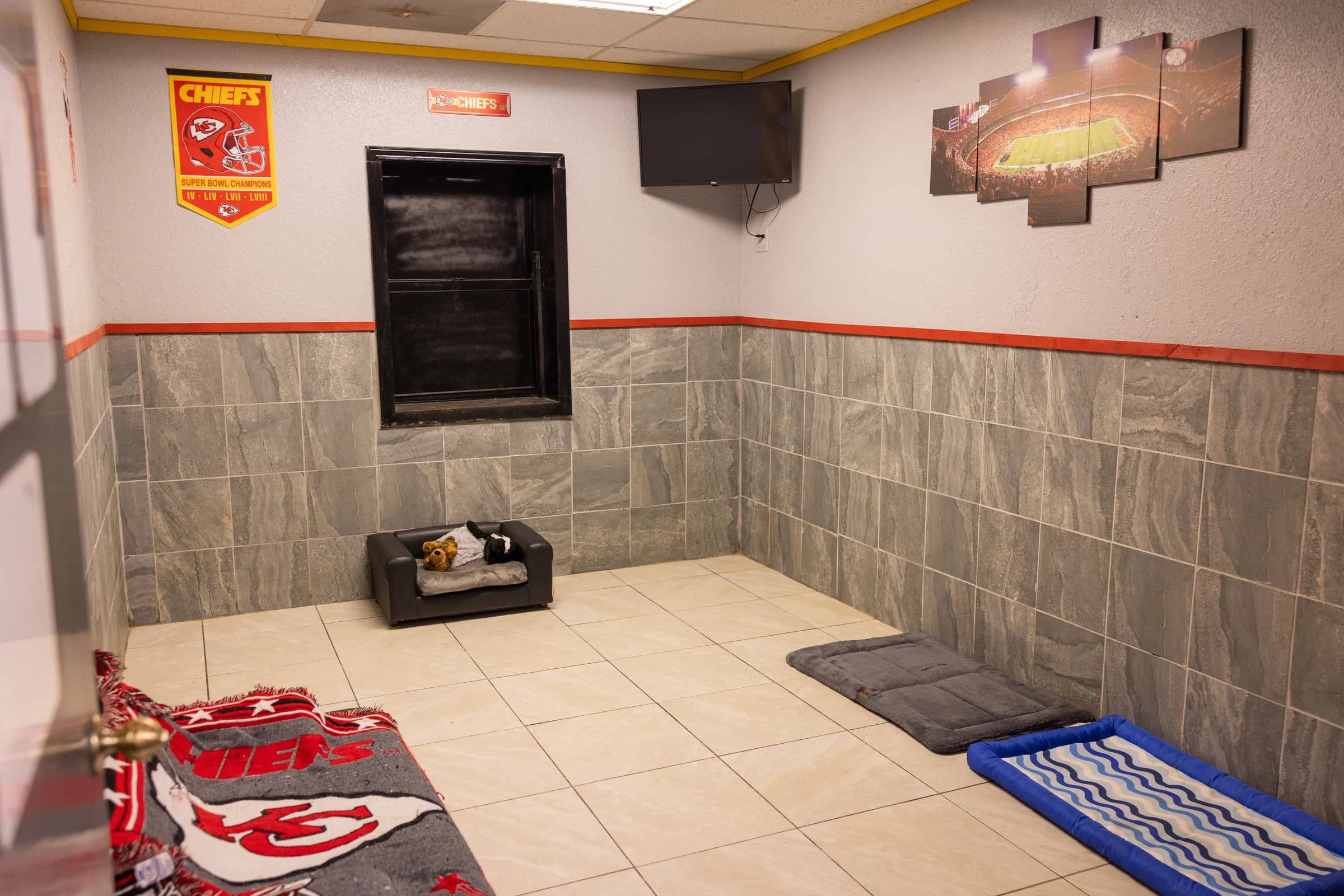 The deluxe Kansas City Chiefs–themed boarding suite at Howliday Inn Pet Resort with a TV and dog beds