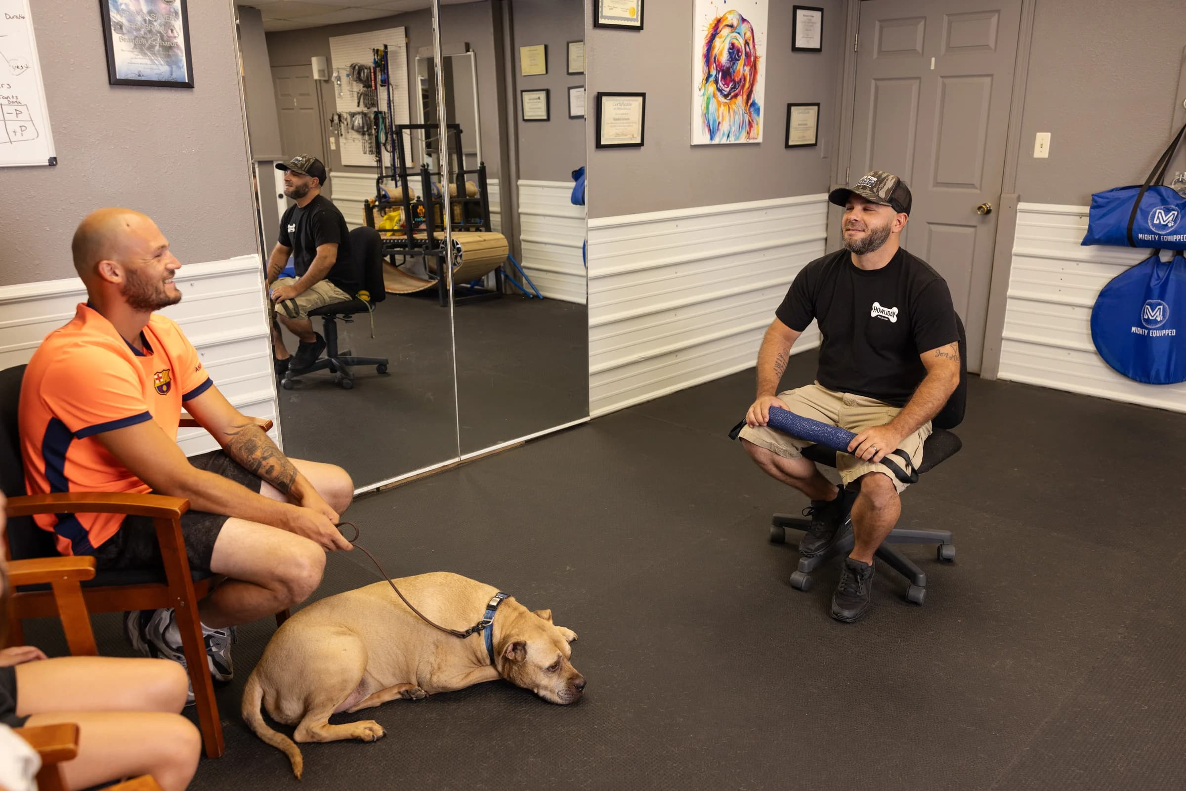 A Howliday Inn trainer working with a client while their dog lies calmly nearby